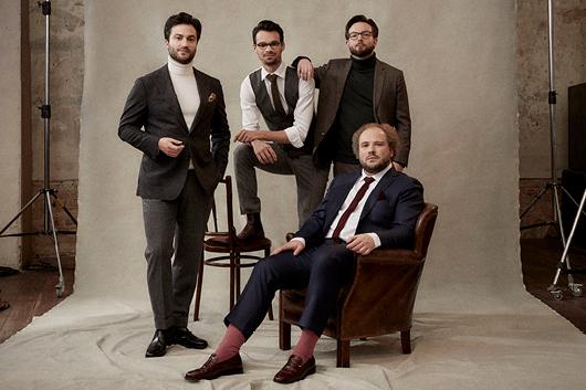 4 people posing in nice clothing in front of beige background